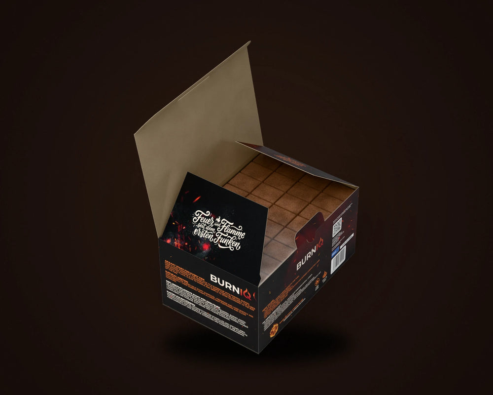 Geöffnete BURNIQ-Box mit Anzündwürfeln auf fünf Platten in Folie